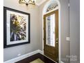Inviting foyer with a modern light fixture, hardwood floors, and a glass-panel wooden front door at 6510 Honeymeade Cir, Charlotte, NC 28277