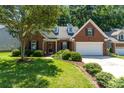 Inviting brick home featuring dormer windows, a two-car garage, and a well-manicured lawn at 9419 Olivia Ln, Charlotte, NC 28277