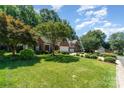 Beautifully landscaped front yard with mature trees enhancing this brick home's curb appeal at 9419 Olivia Ln, Charlotte, NC 28277