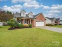Traditional red brick home with a lush front lawn, inviting entrance, and attached two-car garage at 1209 Pressley Downs Se Dr, Concord, NC 28025