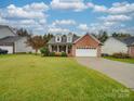 A well-maintained brick home featuring a spacious front yard, covered porch, and an attached two-car garage at 1209 Pressley Downs Se Dr, Concord, NC 28025