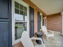 Inviting covered front porch with seating, classic black shutters, and a charming brick exterior at 1209 Pressley Downs Se Dr, Concord, NC 28025