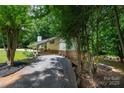 Exterior side view of home with mature trees, gravel driveway, and backyard firepit at 2298 Wintercrest Dr, Rock Hill, SC 29732