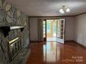 Bright living room featuring a stone fireplace, wood floors, and doorway to the sunroom at 6018 Unionville Rd, Monroe, NC 28110