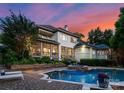 Stunning home exterior with a beautiful pool, spa, and outdoor entertaining area at sunset at 8813 Covey Rise Ct, Charlotte, NC 28226