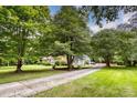Brick home with a long driveway and attached carport nestled among mature trees and greenery at 1010 Forest Dr, Lancaster, SC 29720