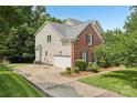 Side view of the brick and siding home featuring an attached garage and paved driveway at 11103 Fountaingrove Dr, Charlotte, NC 28262