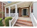 Inviting front porch with brick steps, white railings, and a black front door with sidelights at 11103 Fountaingrove Dr, Charlotte, NC 28262