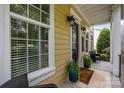 A cozy front porch with seating, potted plants, and a brown door with glass panes at 2009 Waterbury Ln, Waxhaw, NC 28173