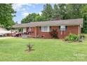 A quaint red brick house is complemented by a lush lawn and mature trees on a sunny day at 2210 Joes Lake Rd, Shelby, NC 28152