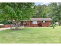 View of the exterior of a brick home with a large tree, lush grass, and a covered parking area at 2210 Joes Lake Rd, Shelby, NC 28152