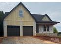 New construction exterior featuring a two-car garage and modern design with a covered porch, set in a gravel driveway at 2589 Polo Ln, Maiden, NC 28650
