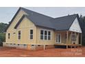 Rear exterior view of a newly constructed home featuring modern design elements, a partially covered porch, and a well-lit backyard at 2589 Polo Ln, Maiden, NC 28650