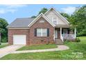 Charming brick home features a covered front porch, attached garage, and well-maintained lawn under a blue sky at 5111 Clearwater Rd, Charlotte, NC 28217