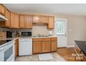 Functional kitchen with wood cabinets, white appliances, and a convenient door to the outside at 5111 Clearwater Rd, Charlotte, NC 28217