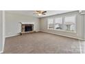 Cozy living room featuring plush carpeting, large windows, and a lovely stone fireplace at 673 Shellbark Dr, Concord, NC 28025