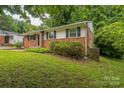 Well-maintained single-story brick home with black shutters and lush, green front yard at 711 September Ln, Charlotte, NC 28208