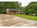Charming single-story home boasting brick accents, dark shutters, and a wide concrete driveway at 711 September Ln, Charlotte, NC 28208