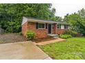 Beautiful single-story brick home with black shutters, a neatly landscaped front yard, and a concrete driveway at 711 September Ln, Charlotte, NC 28208