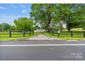 View of home down a driveway, framed by mature trees and a black wooden fence at 956 Stony Point Rd, Kings Mountain, NC 28086