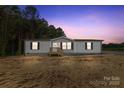 Charming one-story home featuring gray siding, a welcoming front porch, and an expansive treed front lawn at 977 Myers Mill Rd, Olin, NC 28660