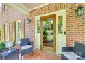 Charming brick porch with brick flooring, seating, front door, and decorative outdoor lighting at 10215 Balmoral Cir, Charlotte, NC 28210