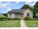Charming bungalow featuring a well-kept lawn, beautiful landscaping, and eye-catching red front door, ideal for a starter home at 1125 Bethel Rd, Charlotte, NC 28208