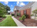 Brick home with a paved walkway, mature shrubs, and garden beds at 1525 Valhalla Dr, Denver, NC 28037