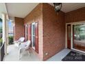 Welcoming brick front porch with white wicker chairs and red shutters at 1525 Valhalla Dr, Denver, NC 28037