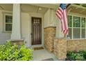 Close-up of the front entrance with a dark wood door, stone accents, and a patriotic American flag at 15344 Cimarron Hills Ln, Charlotte, NC 28278