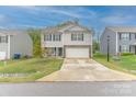 Traditional-style home with a large front yard, attached garage and light colored siding on a sunny day at 2859 Sherrills Stream Dr, Sherrills Ford, NC 28673