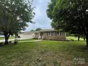 Landscaped front lawn with mature trees framing a charming brick home with an attached garage at 311 Tiffany Nw St, Concord, NC 28027