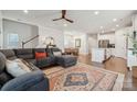 Open-concept living room with hardwood floors, plush gray sectional, and adjacent dining area at 500 Cedar Knoll Cir, Pineville, NC 28134