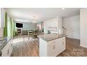 Open-concept kitchen with white cabinets, granite counters, and a seamless transition to the dining and living areas at 711 Saddlebred Ln, Locust, NC 28097