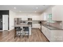 Bright kitchen featuring white cabinetry, granite countertops, stainless appliances, and an island with barstool seating at 711 Saddlebred Ln, Locust, NC 28097