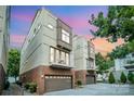 Contemporary townhome exterior featuring a balcony and brick base with an attached garage against a colorful sunset at 925 Westbrook Dr # B, Charlotte, NC 28202