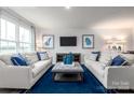 Bright living room featuring large windows, neutral furniture, and a plush blue area rug at 12013 Beaux Art Ln, Charlotte, NC 28214