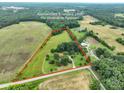 Aerial view of land outlined in red with a two-story home, farmland, trees, and outbuildings at 13101 Pine Bluff Rd, Midland, NC 28107