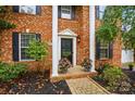 Classic brick home entrance featuring a black front door, white columns, and well-kept landscaping at 14616 Pomerol Ln, Pineville, NC 28134
