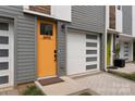 Close-up exterior showcasing the bright orange front door, garage, and modern gray siding of the townhome at 2653 Shenandoah Ave, Charlotte, NC 28205