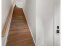 Bright, modern staircase featuring hardwood steps, white walls, and dark hardware on a white door at 2653 Shenandoah Ave, Charlotte, NC 28205