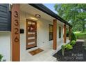 Inviting front porch with a modern wood door, stylish wreath, and manicured landscaping at 3326 Winterfield Pl, Charlotte, NC 28205