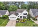 Beautifully landscaped front yard showcasing a two-story home with white siding and a two-car attached garage at 4407 Beauvista Dr, Charlotte, NC 28269