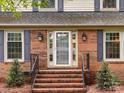 Close-up of the classic brick home's front door with sidelights and freshly landscaped walkway at 6941 Queensberry Dr, Charlotte, NC 28226