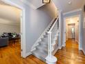 Hallway featuring hardwood floors, a staircase with carpet runner, and doorways to other rooms at 6941 Queensberry Dr, Charlotte, NC 28226