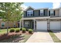 Two-story townhome showcasing an attached one-car garage and fresh landscaping at 7024 Jane Parks Way, Charlotte, NC 28217