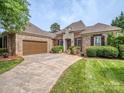 Elegant brick and stone home with a spacious driveway, two-car garage, and manicured lawn and shrubbery at 705 Woburn Abbey Dr, Fort Mill, SC 29715