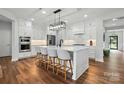 Bright kitchen with an island, modern white cabinetry, stainless steel appliances and hardwood floors at 7322 Vesper Dr, Huntersville, NC 28078