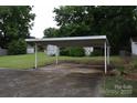 Covered carport on a paved driveway with additional storage buildings in the background, surrounded by greenery at 908 Ravendale Dr, Charlotte, NC 28216