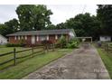 Quaint one-story brick house with a long driveway and ample parking space, set amongst green foliage at 908 Ravendale Dr, Charlotte, NC 28216
